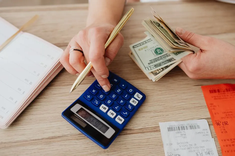 Illustrative photo of a person using a calculator and receipts to plan a budget